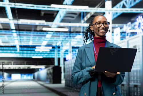 Bild auf Leinwand Smiling data center female engineer configuring server settings with laptop software