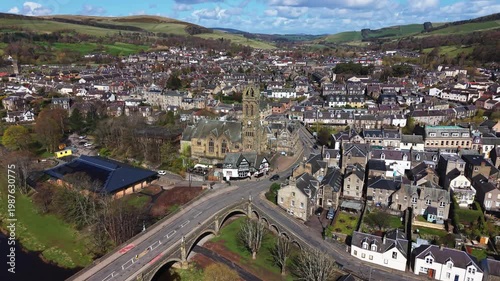 Aerial view of the historic stone Tweed Bridge in Peebles with a traditional church spire and town architecture in the Scottish Borders landscape.