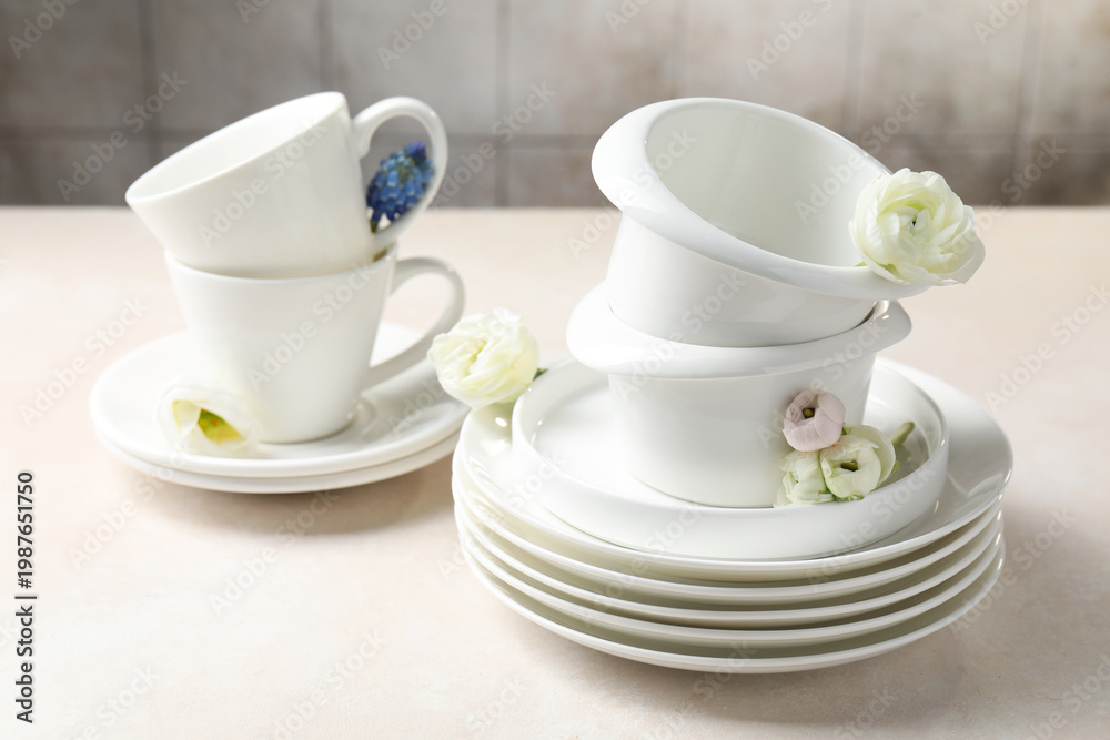 Fototapeta premium Clean dishware and beautiful flowers on light table