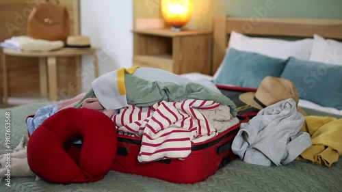 Packing for trip. Putting different clothes into suitcase on bed, closeup