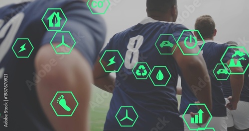 Running athletes in navy jerseys showing 8 with shorts on grassy pitch, with green hexagonal icons