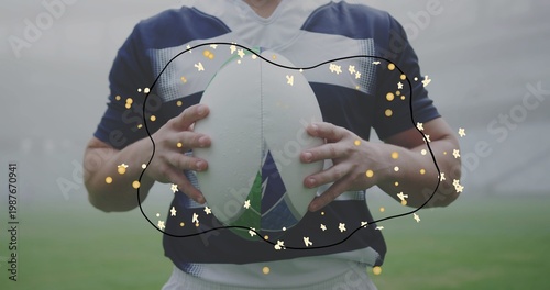 Holding player navy-jersey white-shorts on field, showing white-oval ball, black-outline gold-stars