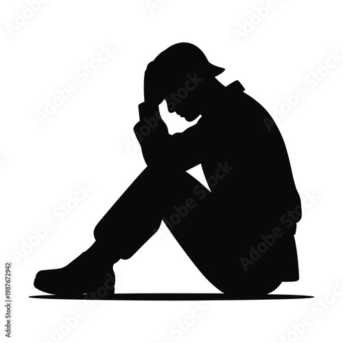 Silhouette of a sad soldier sitting on the ground with head in hands expressing despair