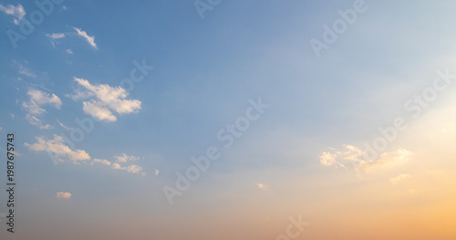 Clear sunset sky with soft orange gradient and small white clouds at twilight for natural background and spiritual concept design