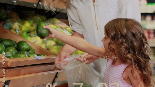 Guiding mom leaning at produce bins, pink kid picking avocados into clear bag, overlays, copy space