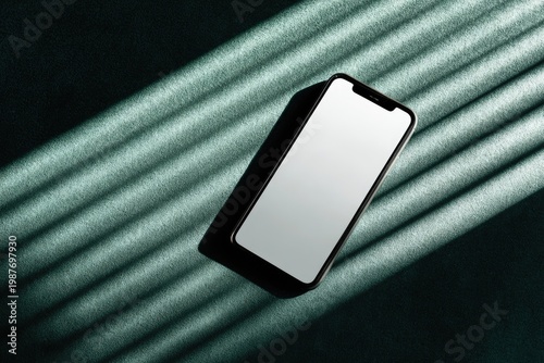 Sleek smartphone with blank screen casts shadow on textured surface