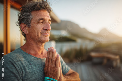 Serene senior man yoga prayer pose outdoor deck mountain sunrise.
