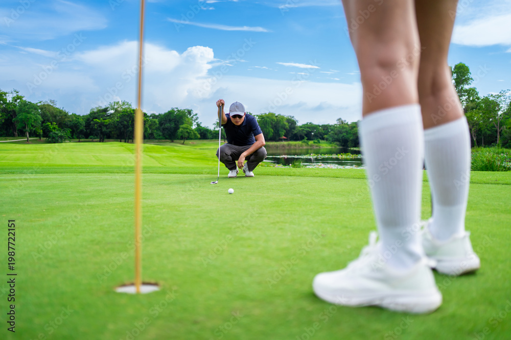 Obraz premium Asian man and woman golfers swing clubs together on scenic golf course. 