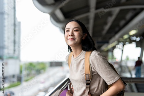Asian young woman standing at train station platform with backpack. 