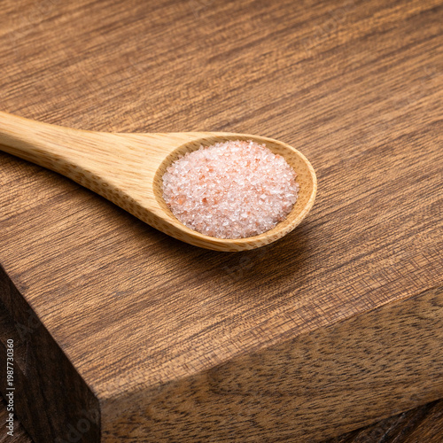 Natural mineral pink salt crystals on a handcrafted spoon, highlighting organic textures and pastel colors.