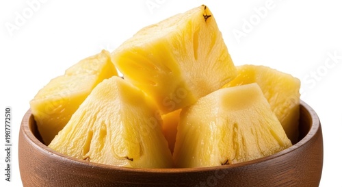 Fresh pineapple chunks piled high in rustic wooden bowl isolated on clean white backdrop.
