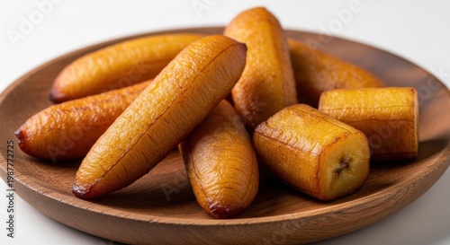 Fried sweet plantains served on round wooden platter against minimalist white background.