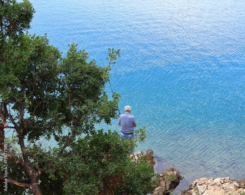 Fisherman with fishing rod on Adriatic coast in Croatia