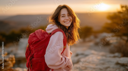 Radiant Hiker at Sunset: A joyful young woman, her face lit by the warm glow of the setting sun, pauses on a scenic trail, her backpack ready for further adventures.