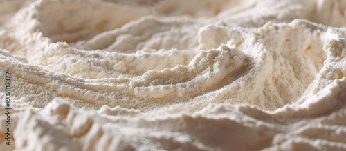 Close-up of a textured, light-colored substance, showing intricate patterns and a soft, undulating surface with subtle shadows. The details are fine and delicate