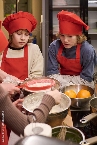 Картината върху платно Vertical shot of Caucasian teenagers learning baking, watching dough preparation in cooking class