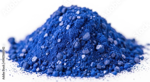 Vibrant blue powder pigments create a textured pile on a white background