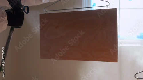 Slow motion view of Worker using a spray gun to apply paint or coating inside cabinet during renovation. Close- p of professional finishing process