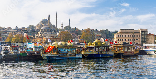 Quadro su tela Traditional Ottoman style fish boats in Eminonu with Suleymaniye Mosque in background, Istanbul, Turkey