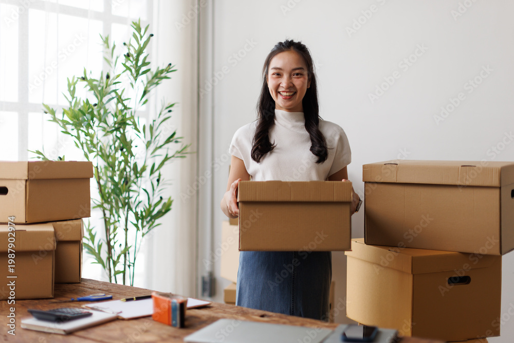 Fototapeta premium Asian woman entrepreneur holding shipping box for e-commerce business
