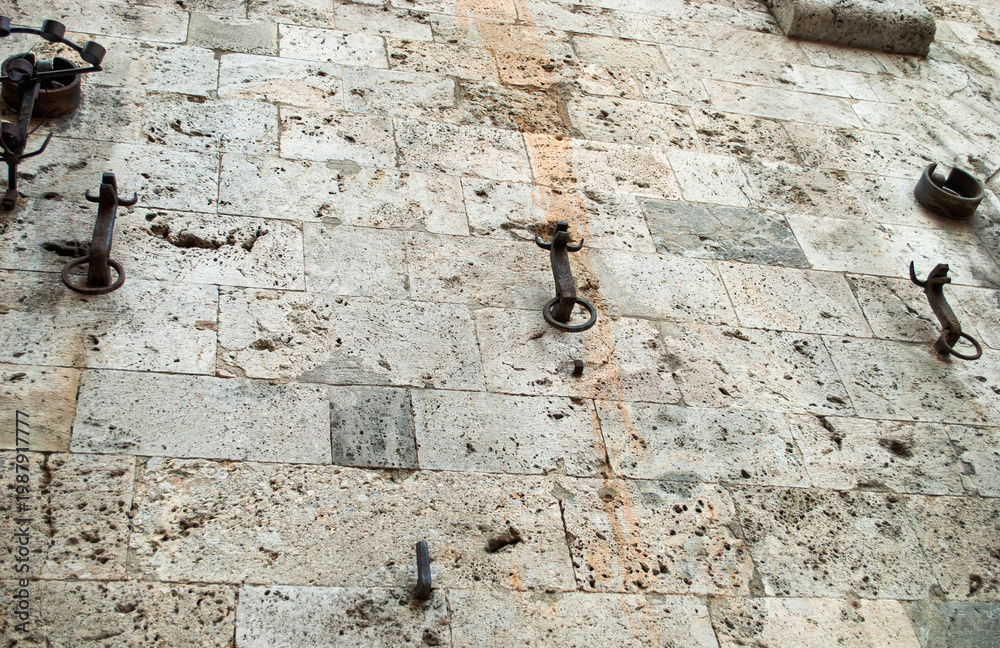 Fototapeta premium ancient wrought iron rings set in a stone wall.