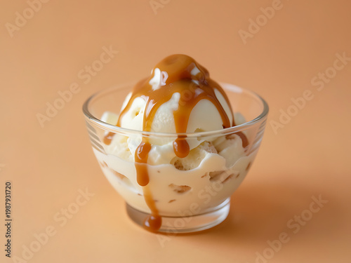 iced dessert with milk drizzle and caramel topping in transparent bowl centered composition on smooth warm tone background 