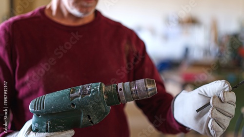Photos Artisan wearing gloves inserting drill bit into power tool
