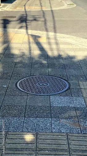 マンホールのある都市の舗装道路に映る木陰の動き