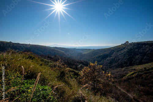 Sun over valley with hills and vegetation in Italy