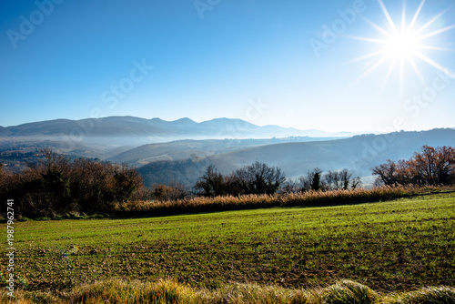 Sunlit field with hills and vegetation in Italy