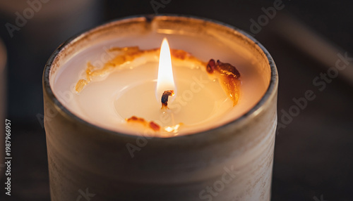 A lit candle with a burning flame and melted wax.