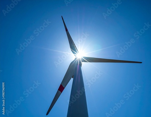 鮮やかな青空に映える風力発電のブレードと太陽の輝き。持続可能な未来へのエネルギー