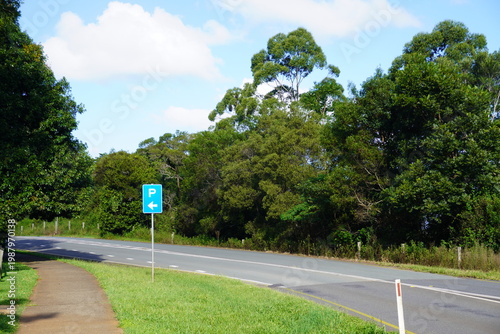 Curving suburban road in Australia with blue parking sign and lush green roadside vegetation