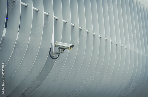 A modern white CCTV security camera mounted outdoors on a building, representing surveillance, protection, and modern technology.