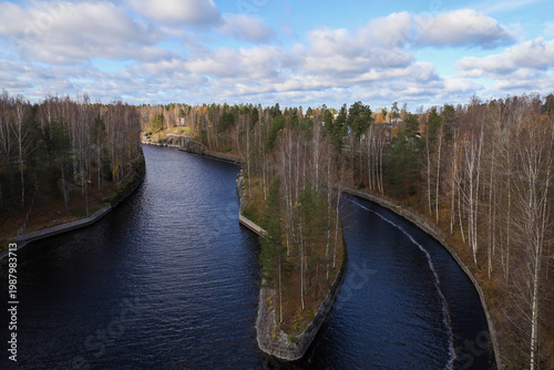 Panoramic aerial view of the Saimaa Canal in autumn, Lappeenranta, Finland. Scenic landscape of the navigable waterway with fall foliage under a cloudy sky. Narrow shipping channel