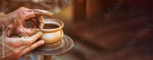 Artisan hands shaping wet clay on a potter's wheel making a pot.