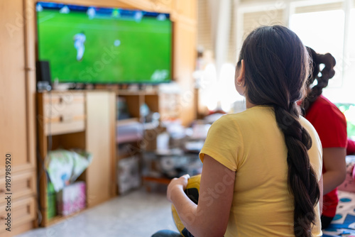 Young woman holding a football, enjoying a soccer game with family on TV