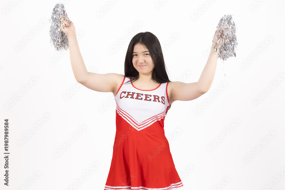 Fototapeta premium Happy cheerleader girl in red uniform holding silver pom poms