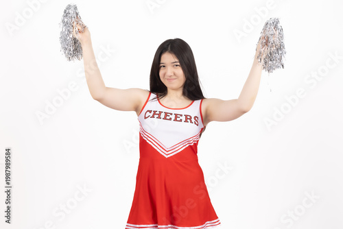 Happy cheerleader girl in red uniform holding silver pom poms