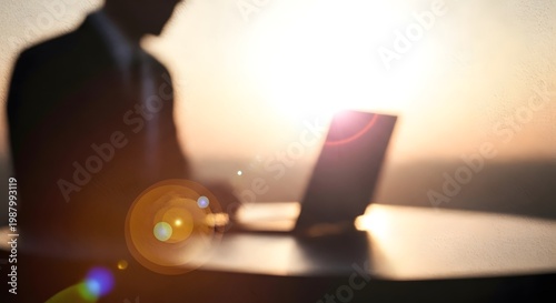 Silhouette of businessman working on laptop at sunset