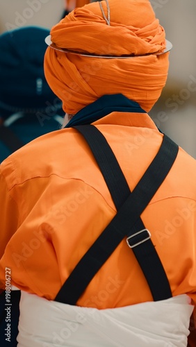 Indian man in orange uniform and turban prays during Vaisakhi