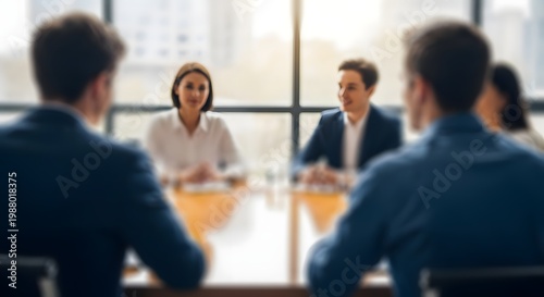 A business meeting in a modern office setting with four professionals engaged in a focused discussion around a table