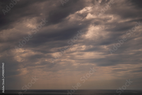 Dramatic cloudy sky over ocean horizon at sunset
