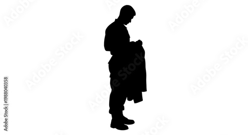 Silhouette of a soldier in uniform holding his jacket, looking down with contemplation