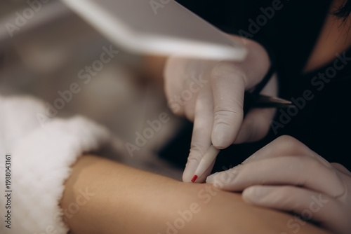 Fotografie Dermatologist performing skin biopsy procedure on patient arm