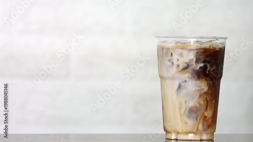 4K Close-up of iced coffee mixed with milk creating beautiful swirl texture Refreshing beverage, Concept ideal for cafe drink menu.