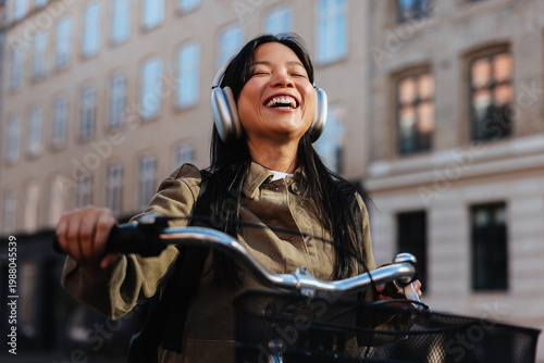 Woman riding a bicycle with headphones smiling in city