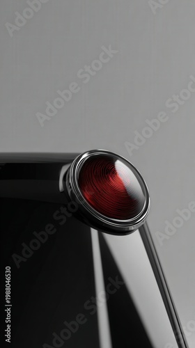 Close up of a glossy red light with silver accents on a smooth black surface