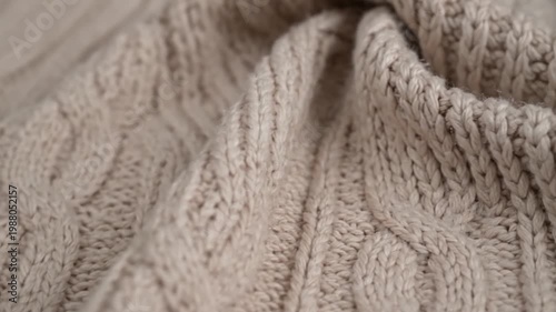 Close up of beige cable knit fabric with intricate textile patterns and soft texture