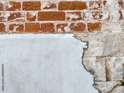 Texture of old brick wall with crumbling plaster. Damaged plaster exposes brick. Abstract background for loft-style interior design. Copy space.